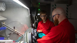 Two researchers standing in front of a fume cupboard