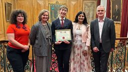 PhD student holding a certificate. He is standing with his supervisors. 