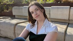 Student sitting on steps in Wave in sunshine 