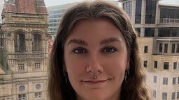 Student smiling with skyline behind 