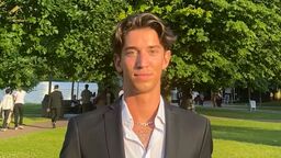 Student Adam Husicka wearing a suit stood in front of trees