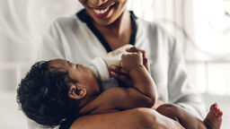 Mother feeding a baby with a bottle.
