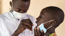 A person swabbing a child's throat.