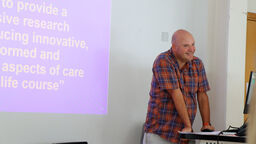 Professor Liam Foster stands at a lecturn in front of a presentation