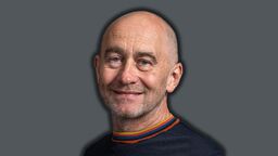 A smiling man on a dark grey background