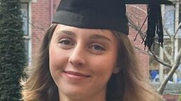 Student Tabitha Wilson in a graduation cap and gown, holding flowers